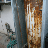 White Water Heater With Orange and Brown Rust Running Down the Front.