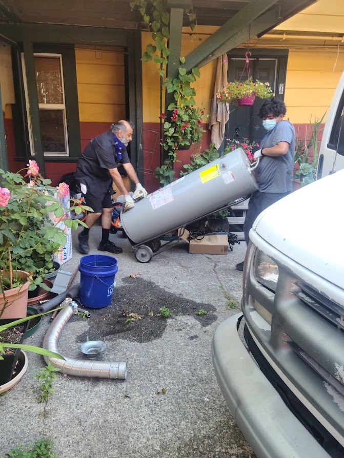 two men wheeling water heater into a house